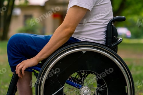 Preview: A young man with disabilities rides in a wheelchair in a city park against a background of trees