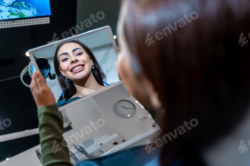 Preview: Patient admiring her perfect smile after teeth whitening treatment