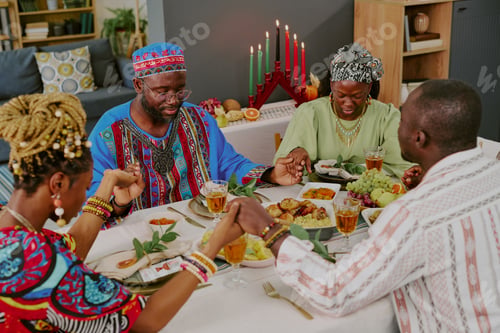 Preview: Black Family Holding Hands Praying Around Table Celebrating Kwanzaa Holiday