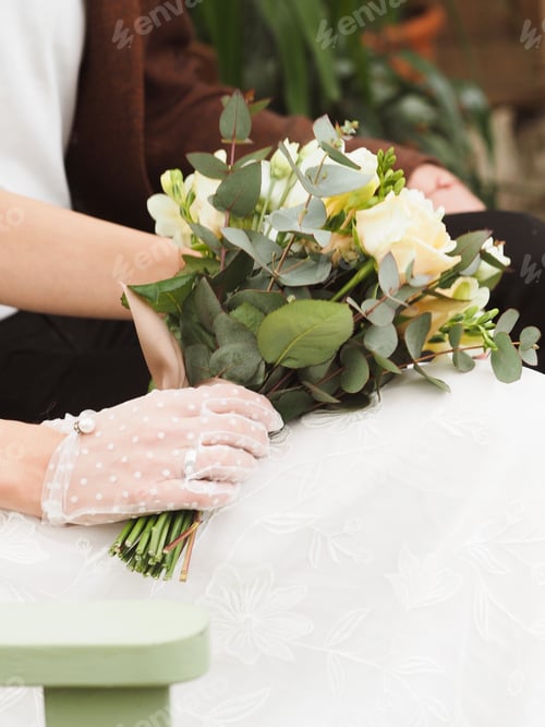 Preview: Close-up of the hands of a bride girl in white gloves, which holds a wedding bouquet.