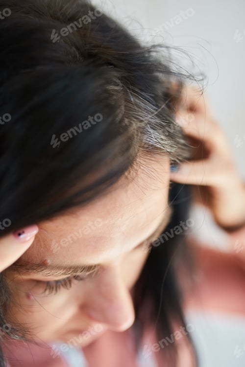 Preview: Portrait of a beautiful young woman examining her scalp and hair in front of the mirror,