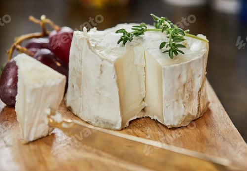 Preview: Selected French cheeses with grapes, on wooden board with rosemary and knife