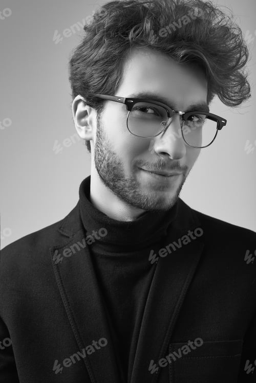 Preview: Fashion Portrait Of Handsome Elegant Man With Curly Hair Wearing Suit And Glasses On Gray