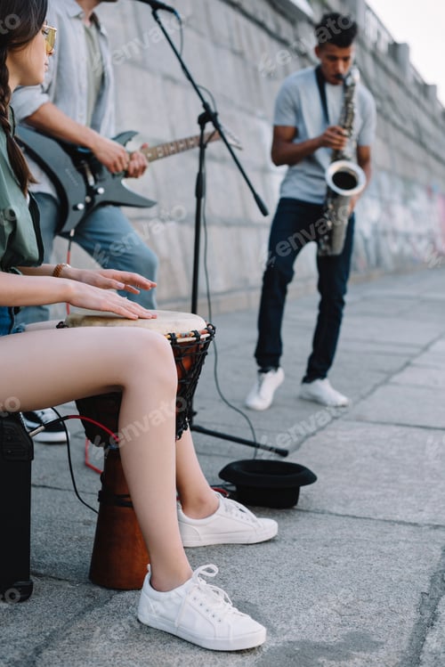 Preview: Talented street musicians with guitar, drum and saxophone performing in city