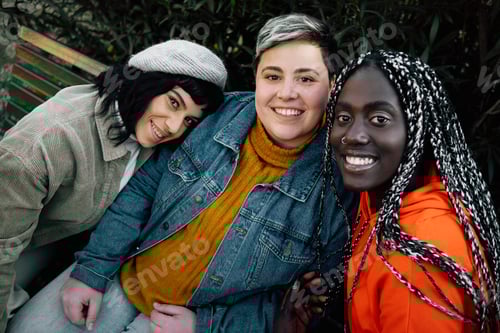 Preview: Multiethnic women smiling watching the camera sitting on a bench