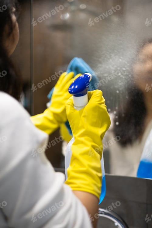 Preview: Cleaning service concept. Close up of female hands in yellow gloves cleaning mirror