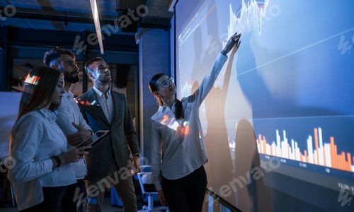 Preview: Holding tablet. Male leader talking to employees, showing the plan on the projector in office
