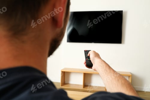 Preview: Young man pressing the TV remote, close up