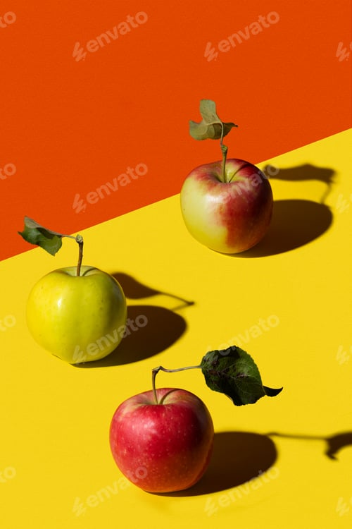Preview: Red, green and red-green apple on a yellow and orange paper background