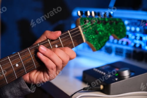 Preview: Close up of musician hand playing electric guitar with at home recording studio.