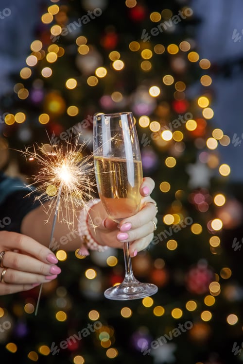 Preview: Champagne in hand against the background of the Christmas tree. Selective focus.