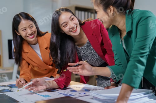 Preview: Three young asian businesswomen are smiling and discussing a project, using charts, graphs and a lap