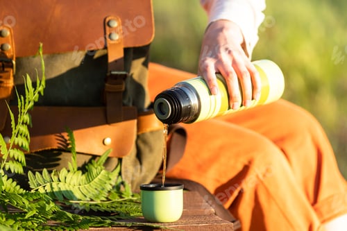 Preview: Naturalist resting on boardwalk drinking tea take a break, enjoying the moment at sunset. Ecotourism