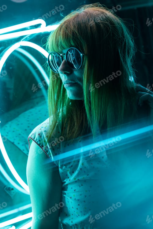 Vorschau: Filmmusik Portrait eines Mädchens mit Sonnenbrille auf Neonlichtern und Reflexionen auf dem Prisma