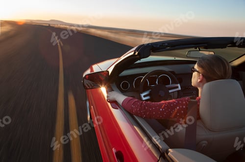 Preview: A view from above looking down on a Caucasian woman driving a convertible sports car.