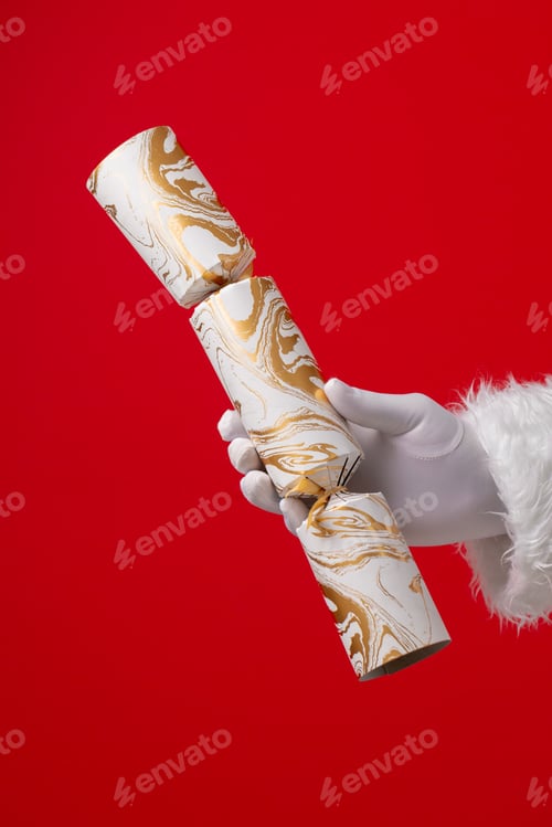 Preview: Image of hand of santa claus holding christmas cracker with copy space on red background
