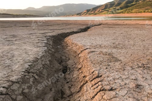 Preview: Dry cracked earth. Drought. The dried-up bottom of the river. Landscape with mountain and lake