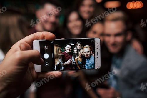 Preview: Focused photo. Picture of girl taking photo of herself and her friends at the party