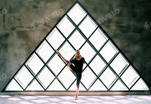 Preview: Young beautiful woman doing yoga asana toe pose variation on large triangular window background