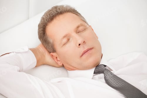 Preview: Sleeping businessman. Tired grey hair man in shirt and tie lying on bed and keeping eyes closed