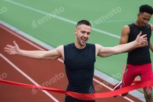 Preview: Cheerful young athlete man crossing finish line