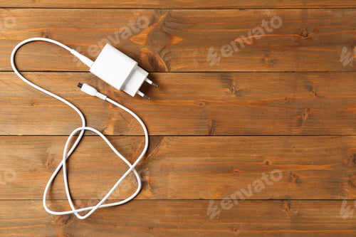 Preview: USB power adapter with charge cable on wooden table, top view. Space for text
