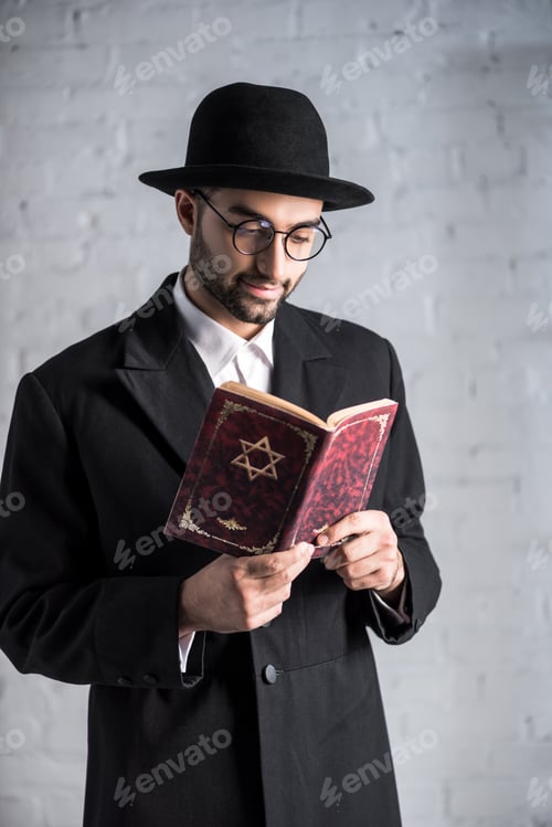 Preview: handsome and smiling jewish man in glasses reading tanakh