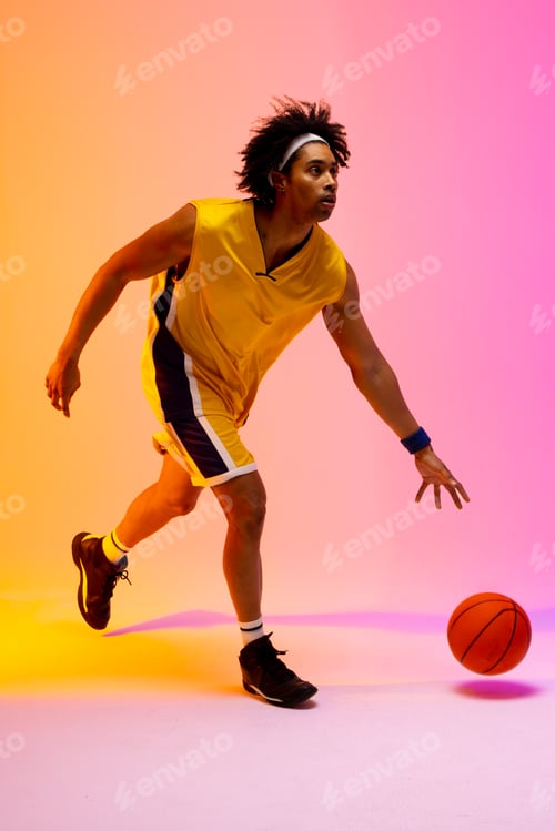Preview: Image of biracial basketball player bouncing basketball on pink to orange background