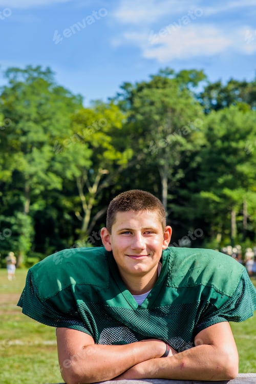 Preview: Portrait teenage male American football player with arms folded at playing field