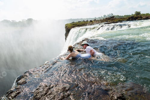 Preview: Man and a girl in water of the Devil's Pool on the edge of Victoria Falls.