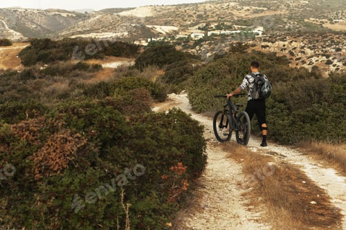 Preview: Professional downhill bicycle rider walking by mountain trail