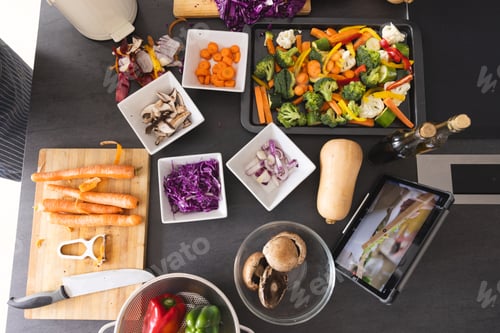 Preview: Fresh vegetables in bowls and tablet with cooking video on screen on kitchen counter at home