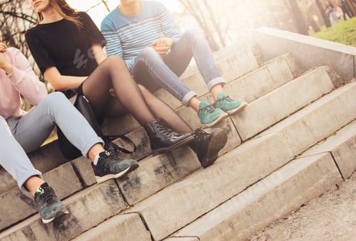 Preview: Crop photo of group of friends Millennials students teenagers sitting at city street