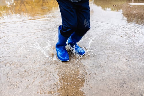 Preview: Boy jumps in a puddle in the street after a rainy day.