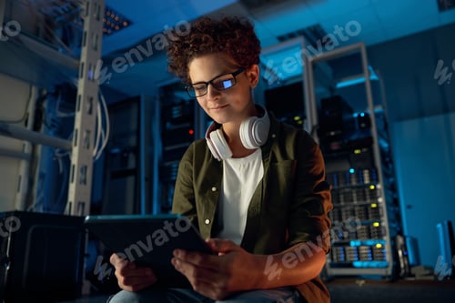 Preview: Teenager guy IT technician working on tablet in server room