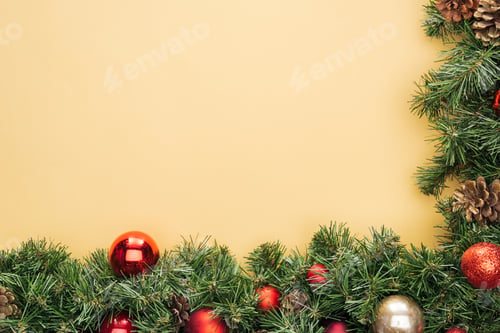 Preview: top view of christmas tree branch with red and golden baubles on yellow background