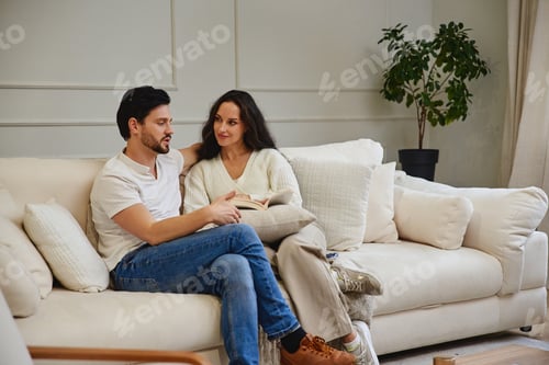 Visualização: Casal aconchegante lendo juntos em um sofá confortável em casa