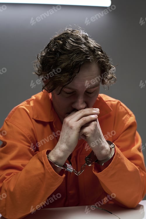 Preview: Pensive Handcuffed Man Sitting Alone in Orange Jumpsuit