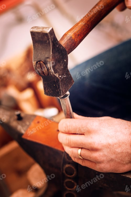 Preview: Craftsperson meticulously shaping wood with a hammer and chisel.