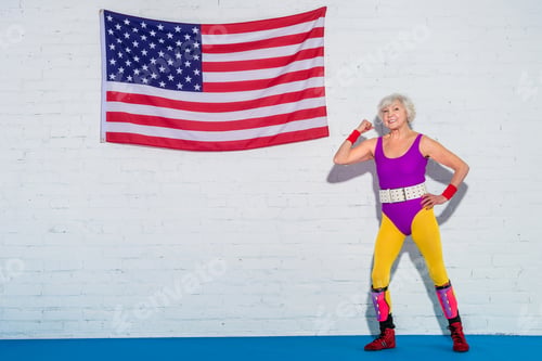 Preview: happy senior woman standing near us flag and smiling at camera