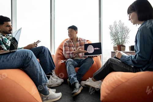 Preview: Male holding laptop with AI picture in office with teammates