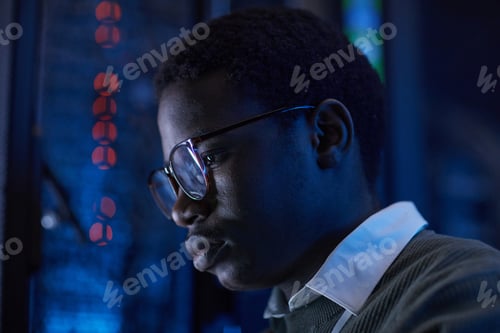 Preview: Focused Young Man Examining Server with Blue Lighting