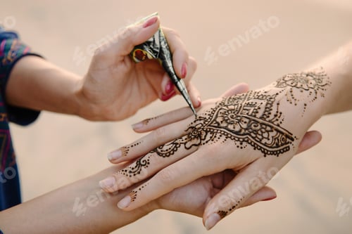 Preview: Artist applying henna tattoo on women hands. Mehndi is traditional Indian decorative art. Close-up