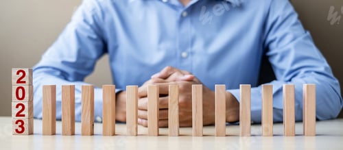 Preview: Businessman hand Stopping Falling of 2023 wooden Blocks.