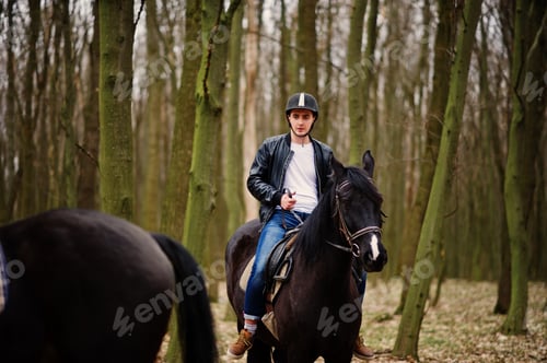 Preview: Young stylish man riding on horses at autumn forest.