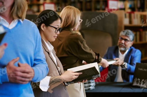 Preview: Young Asian Woman Reading Book While Waiting in Line at Presentation Event