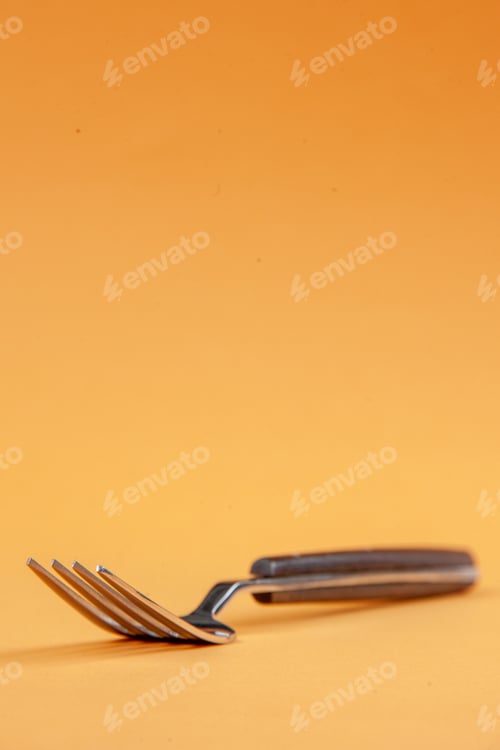 Preview: Vertical view of elegant metal fork on golden background with free space
