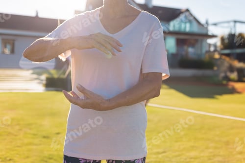 Preview: Senior woman standing on well-maintained lawn in front of modern homes wearing patterned leggings