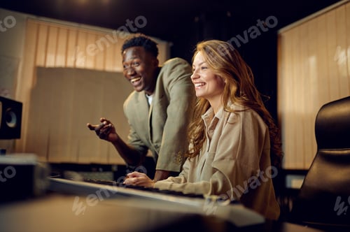 Preview: Two engineers at mixing console, recording studio
