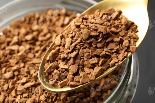 Preview: Adding granulated instant coffee from spoon into jar on grey background, closeup